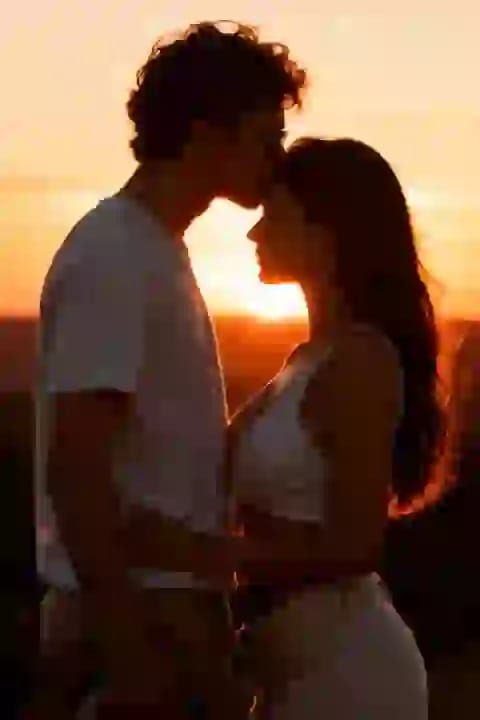 Man with curly hair kissing woman's forehead at sunset. Effect for AI kissing image generator.