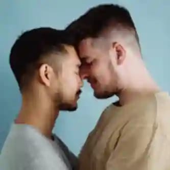 Twee mannen staan ​​intiem tegenover elkaar, hun voorhoofden raken elkaar in een teder moment.
